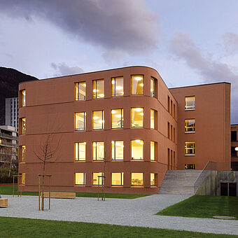 Betonová budova natřená světle oranžovou barvou systému KEIM